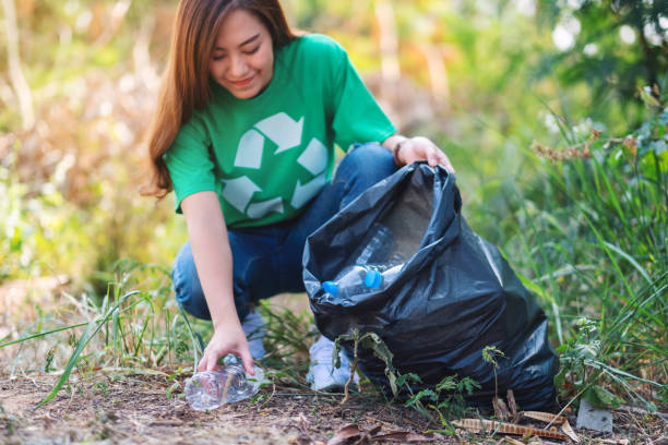 istock woman picking up garbage plastic bottles into a box and bag for recycling concept 1209381340