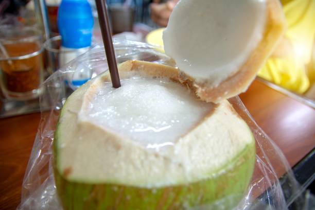 frullato di succo di cocco messo all'interno della frutta di cocco viene posto per il ristoro con paglia - human hand baked food pineapple foto e immagini stock