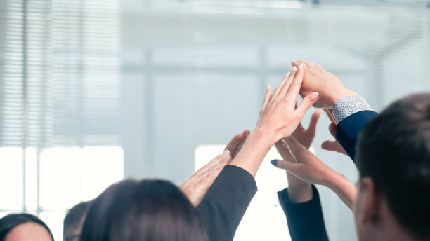 istock close up. a group of employees joining their palms 1209390102