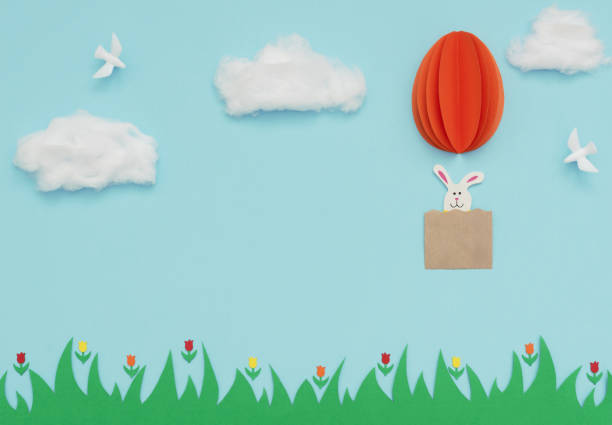 Easter egg hot air balloon made of paper with bunny flies in the blue sky with cotton clouds and white doves over green grass and flowers. Happy Easter holiday concept. Greeting card. Flat lay style. globo de aire caliente huevo de pascua hecho de papel con moscas conejita en el cielo azul con nubes de algodón y palomas blancas sobre hierba verde y flores. feliz concepto de vacaciones de pascua. tarjeta de felicitación. estilo lay plano.