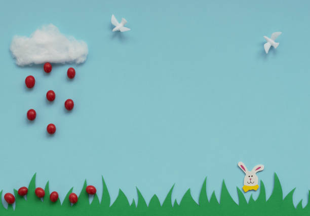 istock Cotton cloud with the rain of small red Easter eggs falling on green grass, Easter bunny and white doves on blue background. Happy Easter holiday concept. Greeting card. Flat lay style with copy space 1209395794