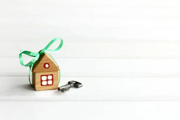 house with a green bow and key on a light background with copy space