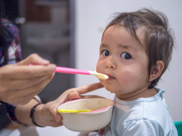 istock Adorable baby eating food and make curious face while look at the camera. 1209402364