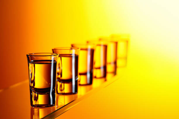 Vodka on a yellow background. Strong alcoholic drink in small glasses.