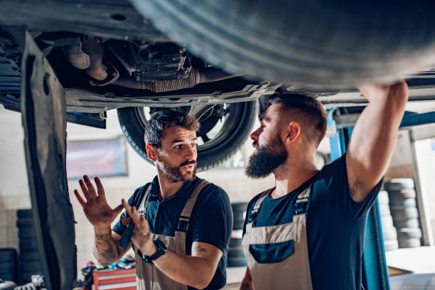 Two mechanics in uniform are working in auto service stock photo
