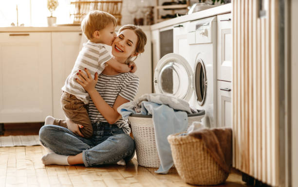 szczęśliwa matka rodzinna gospodyni domowa i dziecko w pralni z pralką - stereotypical housewife little girls family domestic kitchen zdjęcia i obrazy z banku zdjęć