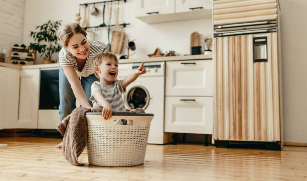 glückliche familie mutter hausfrau und kind in wäscherei mit waschmaschine - domestic life family house residential structure stock-fotos und bilder