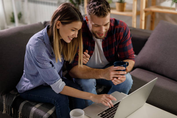 istock Young couple using a laptop while relaxing on the sofa at home 1209424510