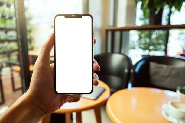 istock a hand holding and showing black mobile phone with blank white screen in cafe 1209424777