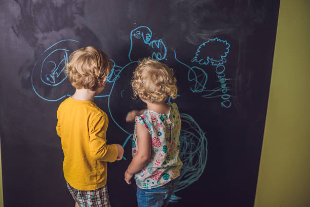 istock Boy and girl paint with chalk on a blackboard 1209425018
