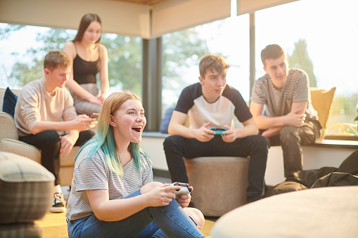 a group of teenage friends play video games in a living room