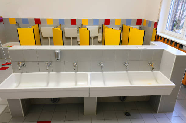 inside a wide bathroom with yellow doors and long wash basin  of a kindergarten