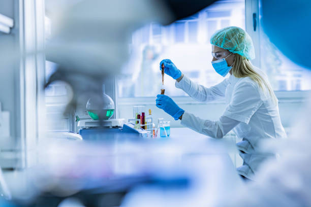 scientifique féminin examinant le liquide toxique dans le laboratoire. - biochimie photos et images de collection