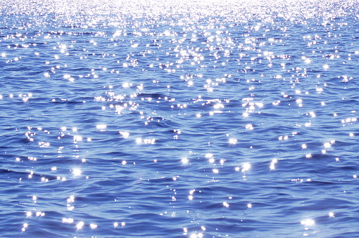 Blue surface of the lake. Sun glare on the water.