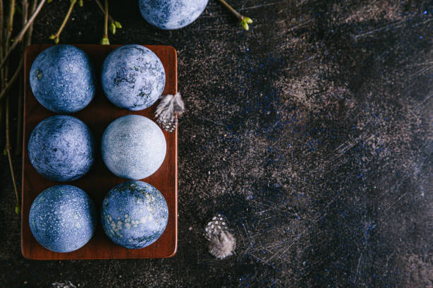 istock Happy easter concept. Multicolored easter painted eggs in blue tones in an egg box and branches with buds on a brown background. 1209428548