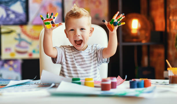 istock funny child boy draws laughing shows hands dirty with paint 1209431302