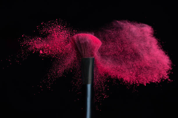 Make-up brush with pink powder explosion isolated in a black background - fotografia de stock