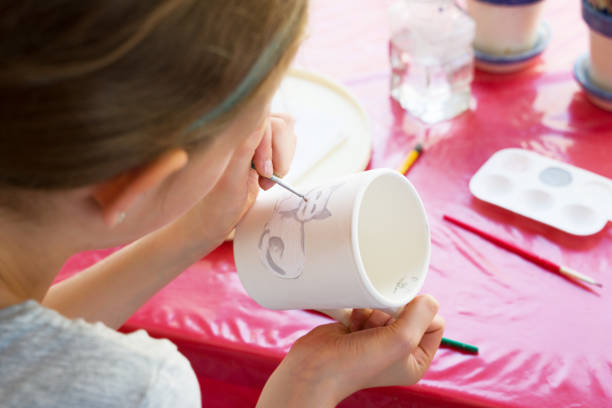 istock Child paints a mug in a pottery workshop. 1209439580