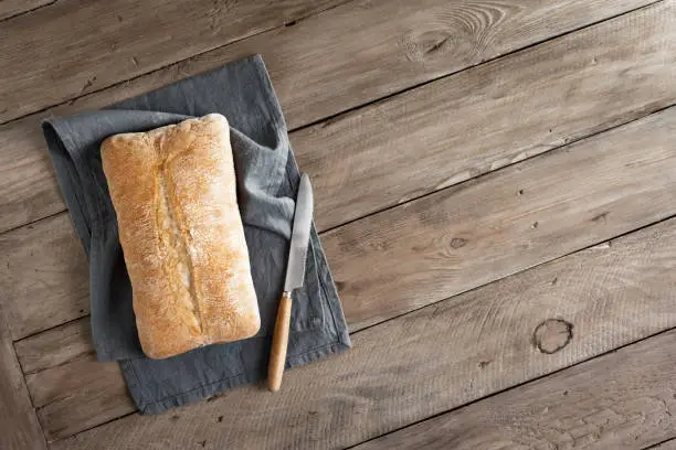 Ciabatta Bread. Fresh Homemade Italian Bread on linen napkin, wooden table, top view, copy space.