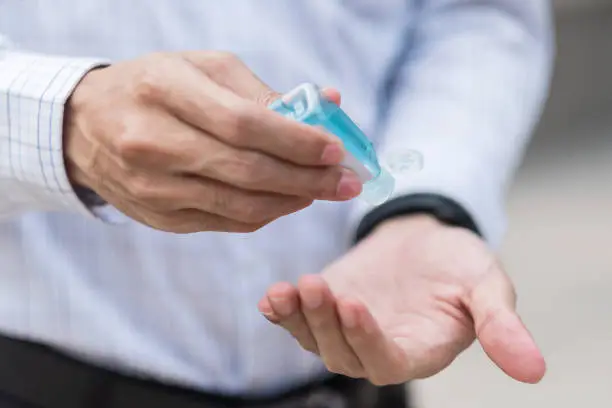 Photo of man hands using wash hand sanitizer gel dispenser, against Novel coronavirus or Corona Virus Disease (Covid-19) at public train station. Antiseptic, Hygiene and Healthcare concept