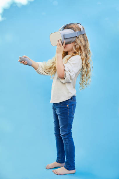 istock Little girl playing with a VR headset on a blue sky background 1209449798