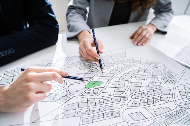 istock Human Hand Holding Pencil Over Cadastre Map 1209449891