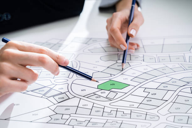 istock Human Hand Holding Pencil Over Cadastre Map 1209449892