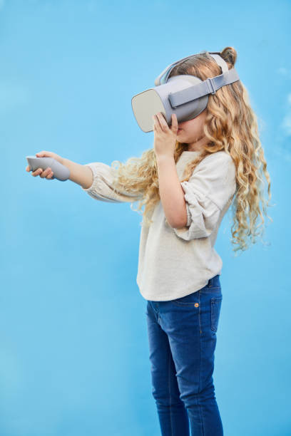 istock Little girl playing with a VR headset on a sky background 1209449946