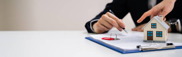 istock Person's Hand Signing Contract With Keys On It 1209450118