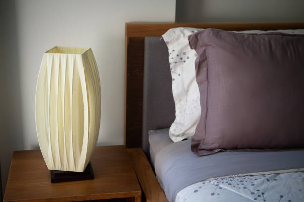 istock Modern lamp on wood table near cozy bed. Close up 1209451147
