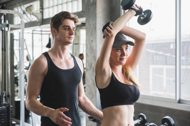istock Attractive woman doing workout with personal trainer at gym. 1209455587