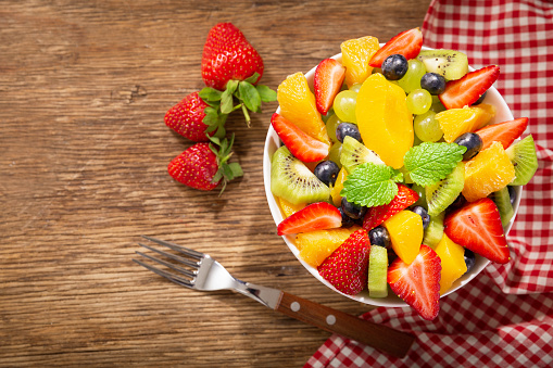 bowl of fruit salad on a wooden table, top view