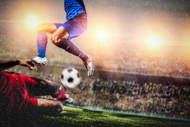 Soccer players performs an action play in stadium Soccer players performs an action play in stadium.Red and blue team player tackle for possession of the ball on supporters background camel colored photos stock pictures, royalty-free photos & images