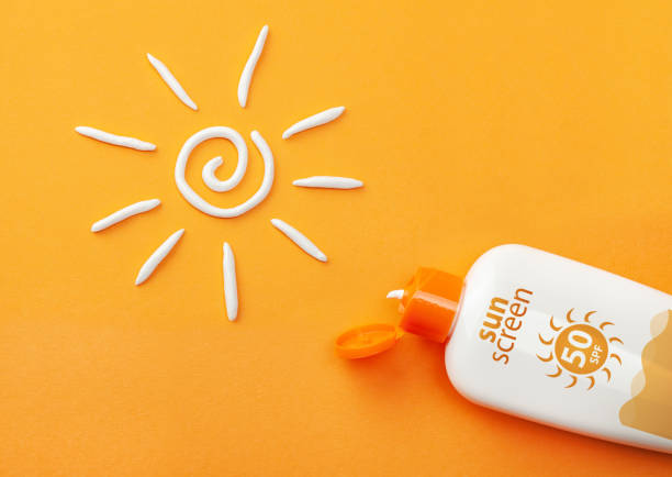 protector solar sobre fondo naranja. botella de plástico de protección solar y crema blanca en forma de sol. - crema de sol fotografías e imágenes de stock