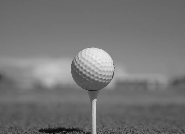 istock Golf ball on tee on golf course over a blurred green field at the sunset. Golf ball on tee over a blurred green field. 1209458982