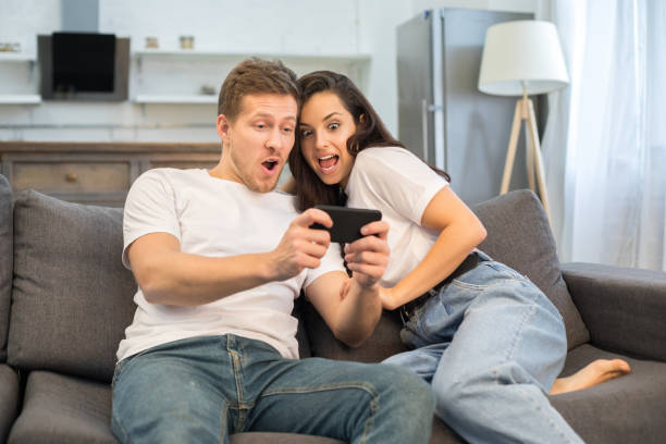 istock Happy young couple using smartphone in their living room 1209458985
