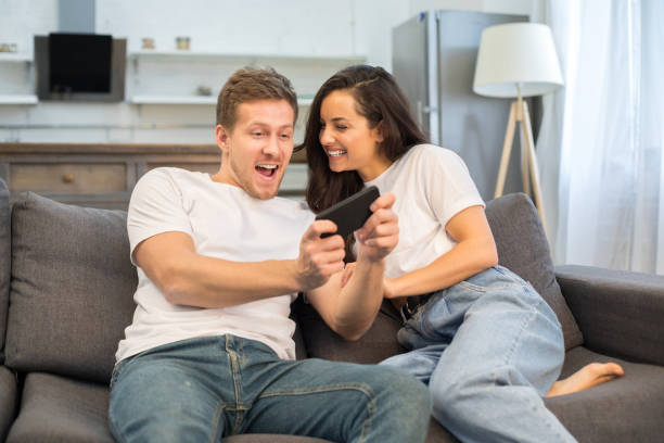 istock Happy young couple using smartphone in their living room 1209459725