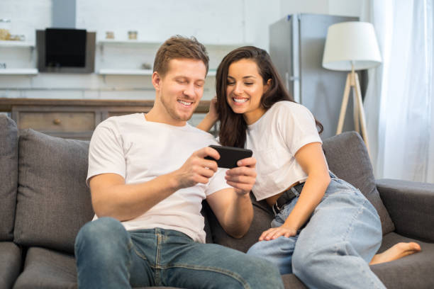 istock Happy young couple using smartphone in their living room 1209459783