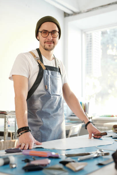 istock Young successful professional leatherworker in apron looking at you by work 1209459859