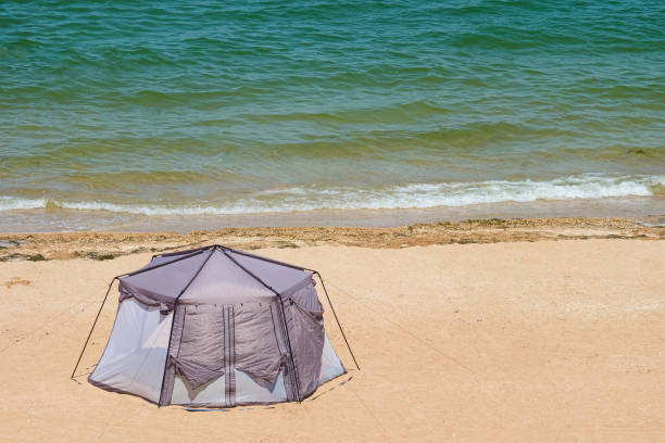 Marquee tent on the sea sandy coast. Summer camping on a beach.