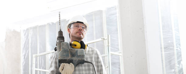 istock man with electric pneumatic drill, professional construction worker with safety hard hat, hearing protection headphones, gloves and protective glasses. look at camera isolated on interior building site background, panoramic image 1209460969