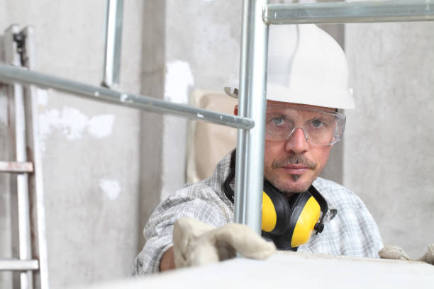 istock man work, professional construction worker  with scaffolding, safety hard hat, hearing protection headphones, gloves and protective glasses. on interior building site background 1209460985