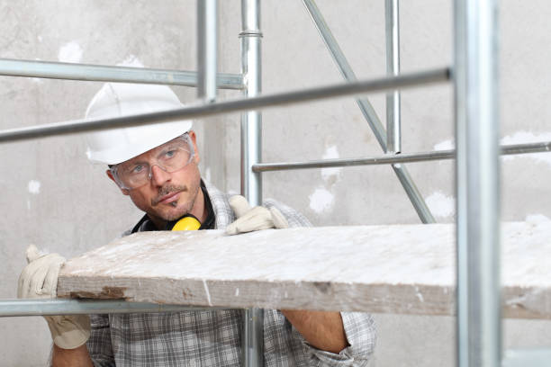 istock man work, professional construction worker  with scaffolding, safety hard hat, hearing protection headphones, gloves and protective glasses. on interior building site background 1209460990