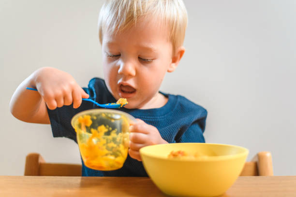 istock Cute Little Boy Eating in Kitchen 1209462453