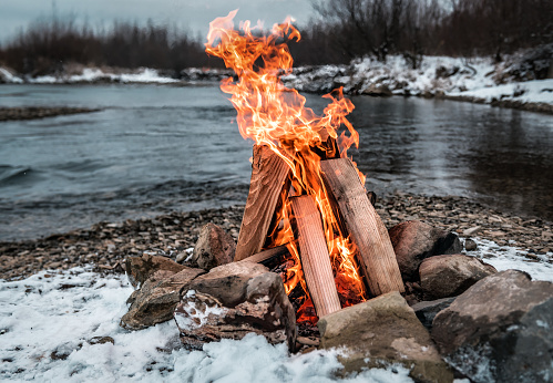 campfire on the winter snowy river bank