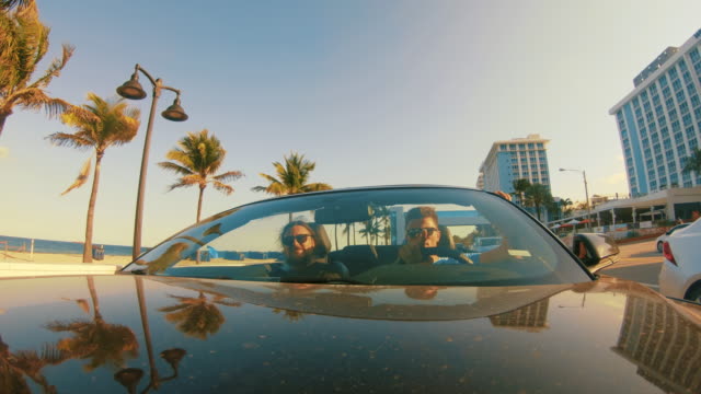 MS Men driving convertible on sunny street, Miami, Florida, USA