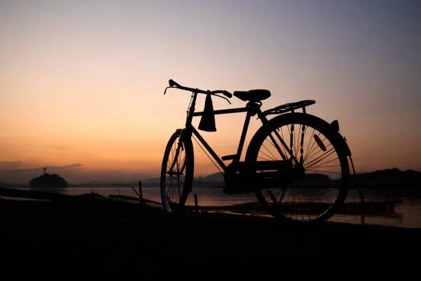 Photo of A bicycle in the banks of a river at sunset