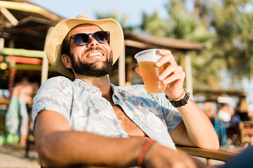 Young handsome man enjoying beer in beach bar