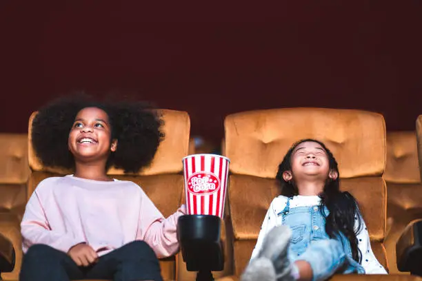 Happy and funny kid with popcorn watch cinema in movie theater