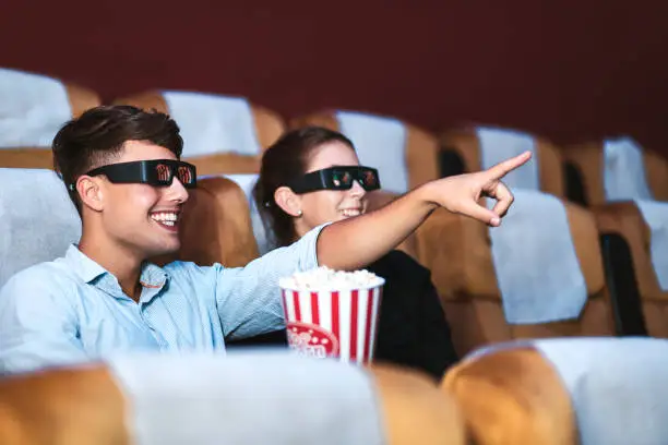 Happy young love couple with 3D glass and popcorn watch cinema in movie theater